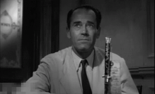a man in a suit and tie is holding a clarinet in his right hand .