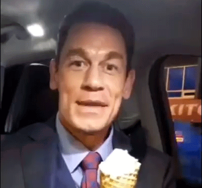 A Man In A Suit And Tie Is Holding A Cone Of Ice Cream . GIF