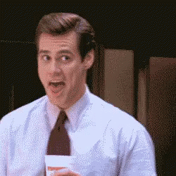 A Man In A Suit And Tie Is Holding A Cup And Making A Funny Face GIF