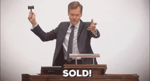 A Man In A Suit And Tie Is Holding A Gavel At An Auction . GIF