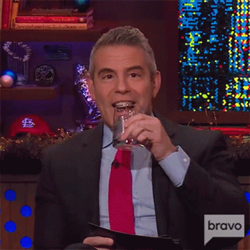 a man in a suit and tie is holding a glass and a clipboard with the word bravo on it .