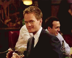 A Man In A Suit And Tie Is Holding A Glass In His Hand GIF