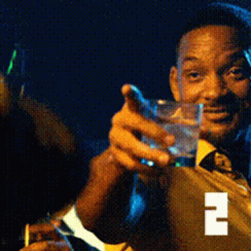 A Man In A Suit And Tie Is Holding A Glass Of Water And A Cigarette GIF