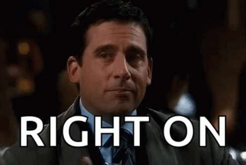A Man In A Suit And Tie Is Holding A Glass Of Whiskey And Pointing At It . GIF