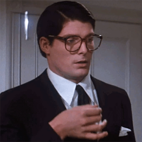 A Man In A Suit And Tie Is Holding A Glass Of Wine GIF