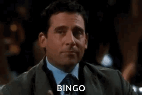 A Man In A Suit And Tie Is Holding A Glass Of Wine And Saying `` Bingo '' . GIF