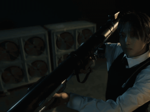 A Man In A Suit And Tie Is Holding A Gun In His Hand GIF