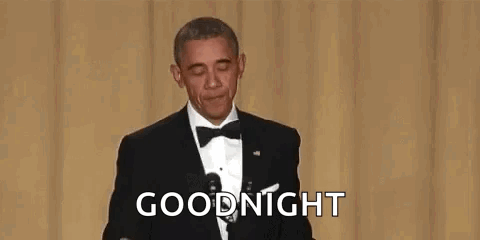 A Man In A Suit And Tie Is Holding A Microphone And Covering His Mouth . GIF