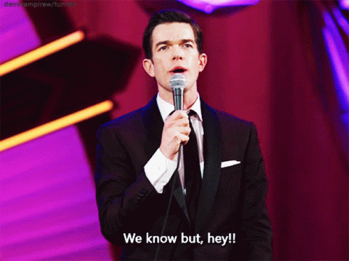 A Man In A Suit And Tie Is Holding A Microphone And Says We Know But Hey GIF