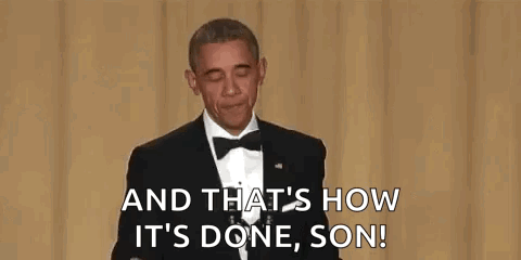 A Man In A Suit And Tie Is Holding A Microphone In His Hand And Talking Into It . GIF