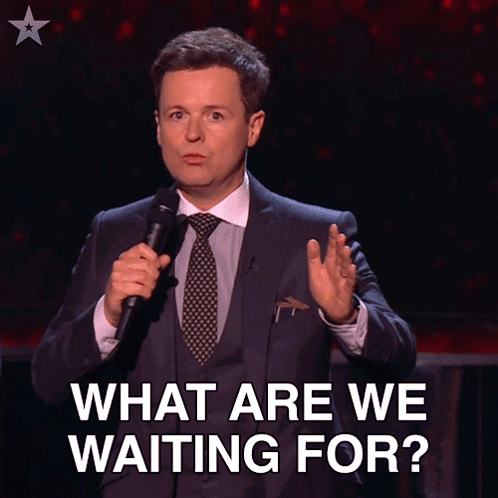 A Man In A Suit And Tie Is Holding A Microphone With The Words Let 'S Get Going Below Him GIF