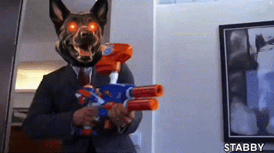 A Man In A Suit And Tie Is Holding A Nerf Gun . GIF