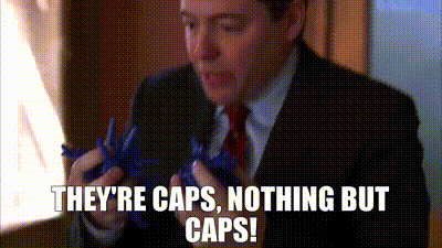 A Man In A Suit And Tie Is Holding A Pair Of Scissors And Says They 'Re Caps , Nothing But Caps GIF