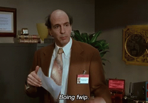 A Man In A Suit And Tie Is Holding A Piece Of Paper And Says Boing Fwip GIF