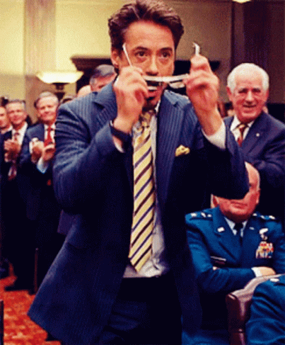 a man in a suit and tie is holding a piece of paper in his mouth