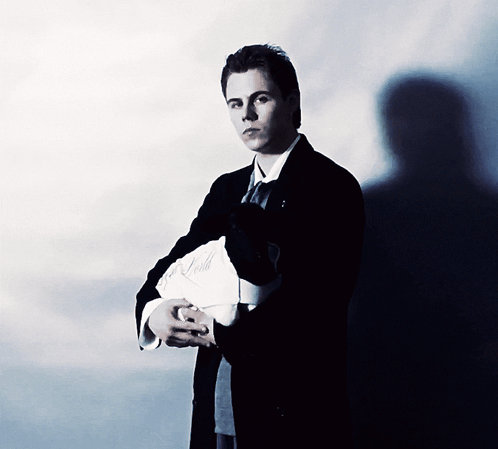 A Man In A Suit And Tie Is Holding A Piece Of Paper That Says ' A. Smith ' On It GIF