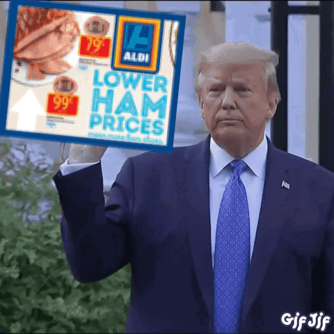 A Man In A Suit And Tie Is Holding A Sign That Says Lower Ham Prices GIF