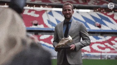 a man in a suit and tie is holding a soccer boot