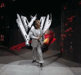 A Man In A Suit And Tie Is Holding A Sword In Front Of A Wwe Logo GIF