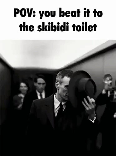 A Man In A Suit And Tie Is Holding A Top Hat In Front Of His Face While Walking Down An Elevator . GIF