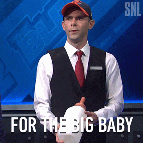 A Man In A Suit And Tie Is Holding A White Hat With The Words For The Big Baby Written Below Him GIF