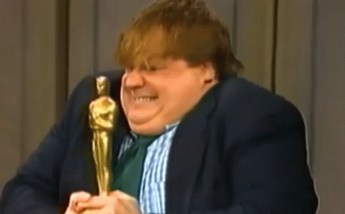 A Man In A Suit And Tie Is Holding An Oscar Statue And Talking Into A Microphone . GIF