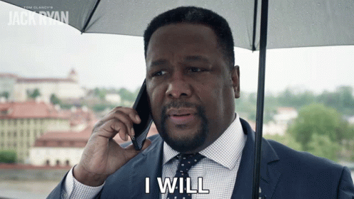 A Man In A Suit And Tie Is Holding An Umbrella And Talking On A Cell Phone With The Words I Will Below Him GIF