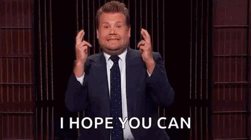 A Man In A Suit And Tie Is Holding His Fingers Crossed While Giving A Speech . GIF