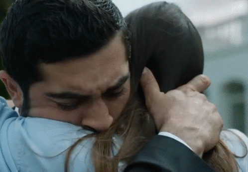 A Man In A Suit And Tie Is Hugging A Woman In A Blue Shirt GIF