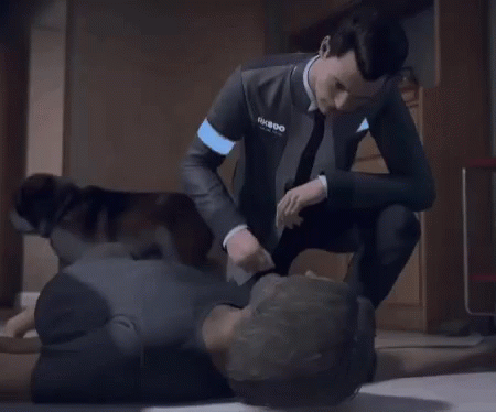 A Man In A Suit And Tie Is Kneeling Down Next To Another Man Laying On The Floor . GIF