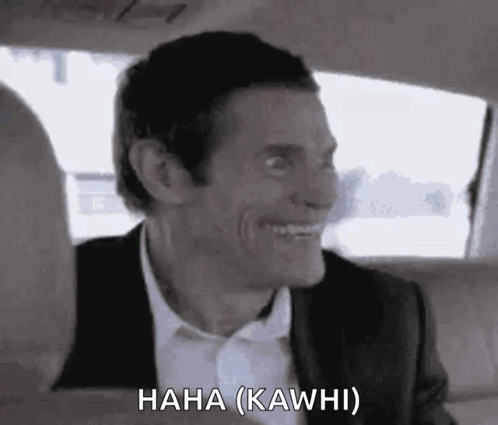 A Man In A Suit And Tie Is Laughing In A Car . GIF