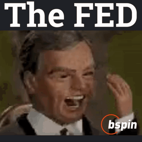 A Man In A Suit And Tie Is Laughing In Front Of The Fed Logo GIF