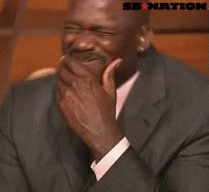 A Man In A Suit And Tie Is Laughing With A Sb Nation Logo Behind Him . GIF