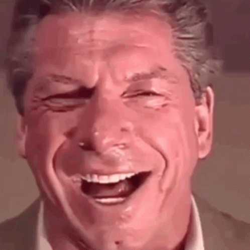 A Man In A Suit And Tie Is Laughing With His Eyes Closed . GIF