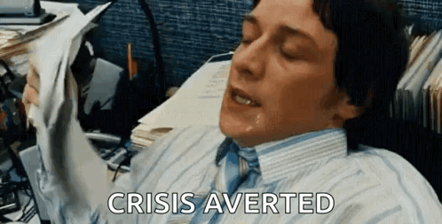 A Man In A Suit And Tie Is Laying On A Desk With A Bunch Of Papers And Says Crisis Averted GIF