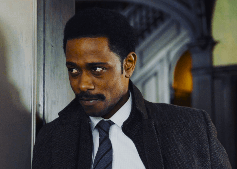 A Man In A Suit And Tie Is Leaning Against A Door GIF