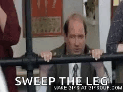 A Man In A Suit And Tie Is Leaning On A Railing And Says `` Sweep The Leg '' . GIF