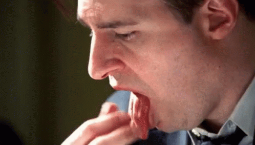 A Man In A Suit And Tie Is Licking His Hand . GIF