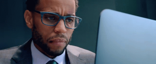 A Man In A Suit And Tie Is Looking At A Laptop GIF