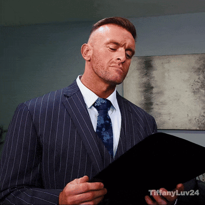 A Man In A Suit And Tie Is Looking At A Piece Of Paper With Tiffanyluv24 Written On The Bottom Right GIF