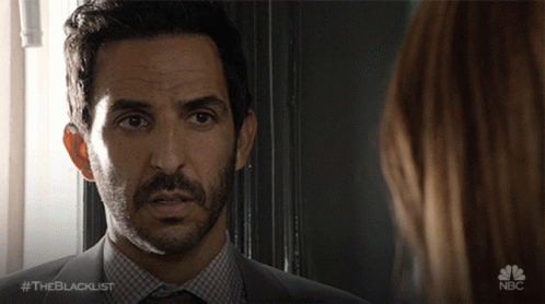 A Man In A Suit And Tie Is Looking At A Woman With The Blacklist Written On The Bottom GIF