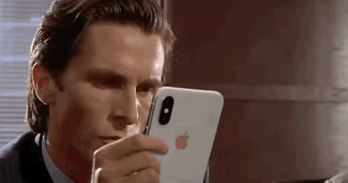 a man in a suit and tie is looking at his iphone .