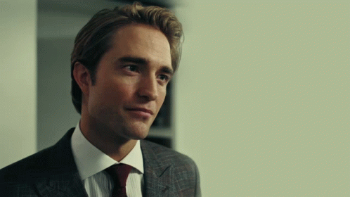 A Man In A Suit And Tie Is Looking At Something GIF