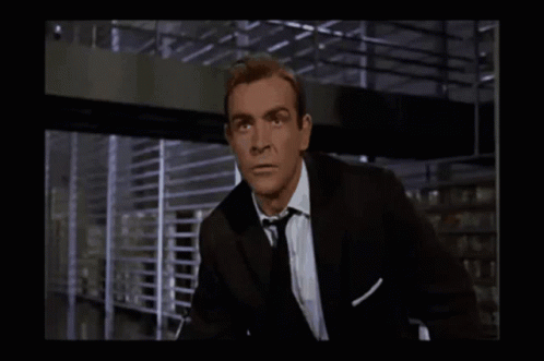 A Man In A Suit And Tie Is Looking At Something GIF