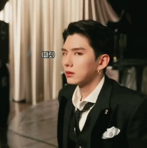 A Man In A Suit And Tie Is Looking At Something GIF