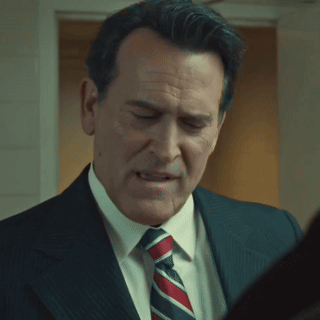 A Man In A Suit And Tie Is Looking At Something GIF