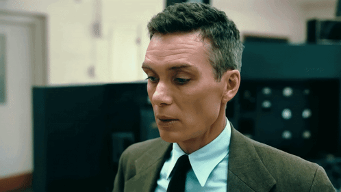 A Man In A Suit And Tie Is Looking At Something GIF
