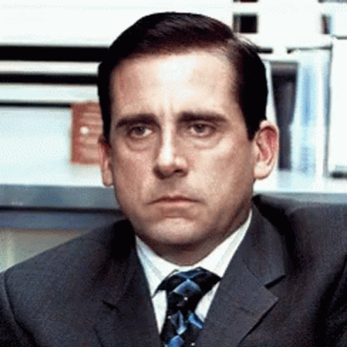 A Man In A Suit And Tie Is Looking At Something GIF