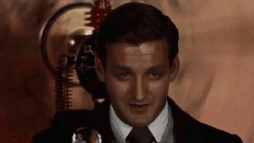 A Man In A Suit And Tie Is Looking At Something GIF
