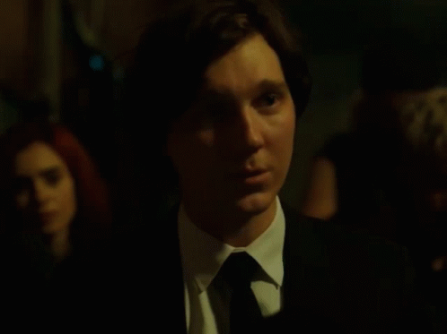 A Man In A Suit And Tie Is Looking At Something GIF